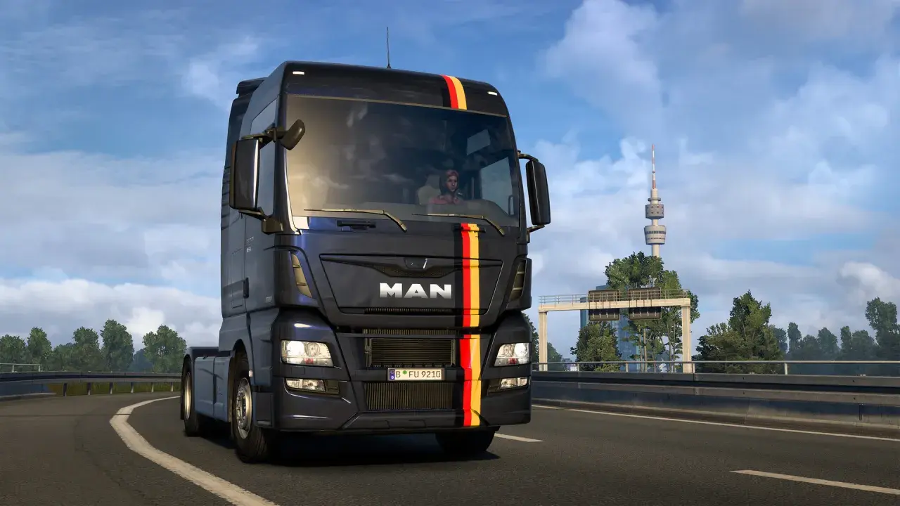 Ciemny MAN z niemieckimi barwami na masce jedzie autostradą. W tle wieża telewizyjna, typowa dla krajobrazu w grze german truck simulator.