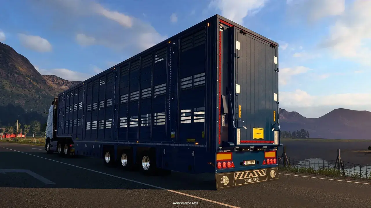 Ciemnoniebieska naczepa do przewozu zwierząt w grze ets2 scs, jadąca malowniczą drogą.