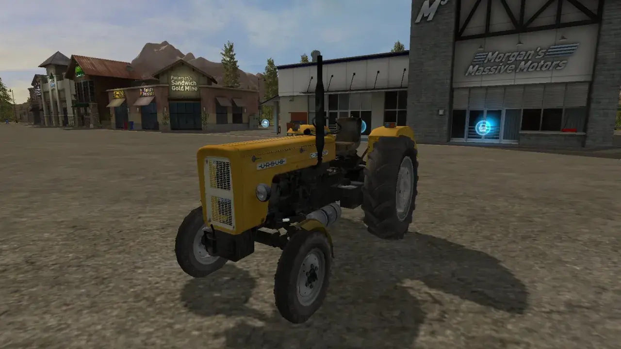 Żółty Ursus C-360 FS17 na placu przed budynkami.