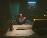 W cyberpunkowym domu lalek, Woodman siedzi w fotelu, groźnie patrząc. Na biurku leży klawiatura, a obok smoczy posąg.