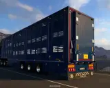 Ciemnoniebieska naczepa do przewozu zwierząt w grze ets2 scs, jadąca malowniczą drogą.