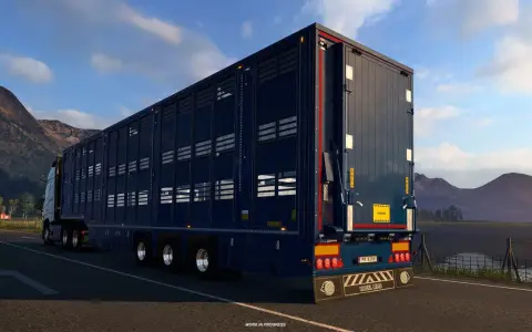 Ciemnoniebieska naczepa do przewozu zwierząt w grze ets2 scs, jadąca malowniczą drogą.