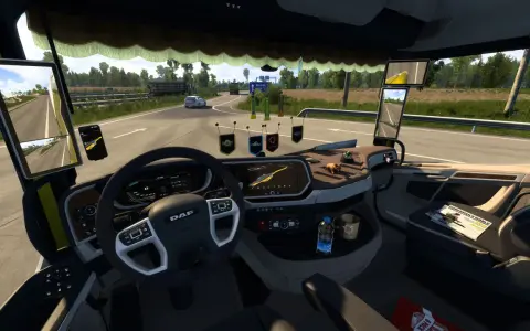 Wnętrze ciężarówki z widokiem na drogę. Na desce rozdzielczej widoczne są różne cabin accessories ets2, w tym nawigacja, telefon i ozdoby.