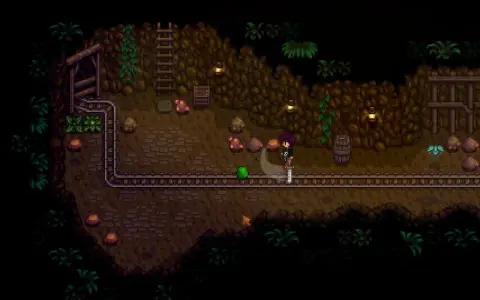 Postać w kopalni Stardew Valley walczy z zielonym potworem. To świetny moment na poradnik!