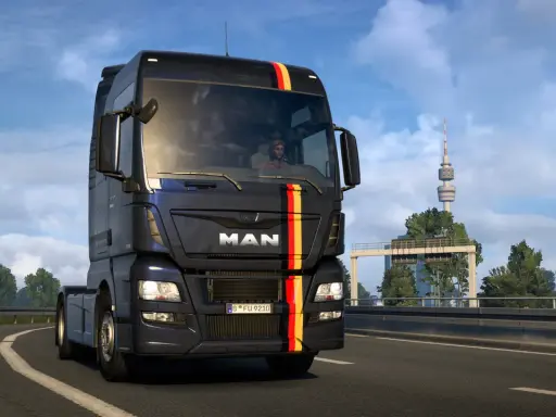 Ciemny MAN z niemieckimi barwami na masce jedzie autostradą. W tle wieża telewizyjna, typowa dla krajobrazu w grze german truck simulator.