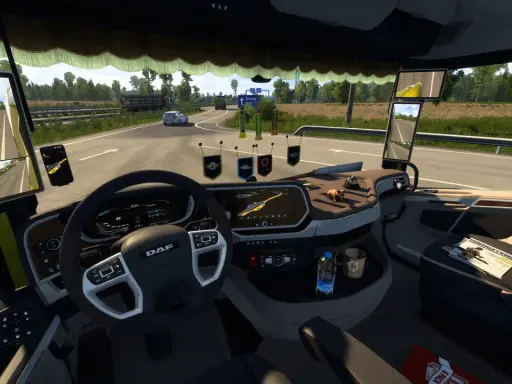 Wnętrze ciężarówki z widokiem na drogę. Na desce rozdzielczej widoczne są różne cabin accessories ets2, w tym nawigacja, telefon i ozdoby.