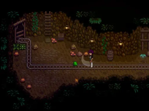 Postać w kopalni Stardew Valley walczy z zielonym potworem. To świetny moment na poradnik!