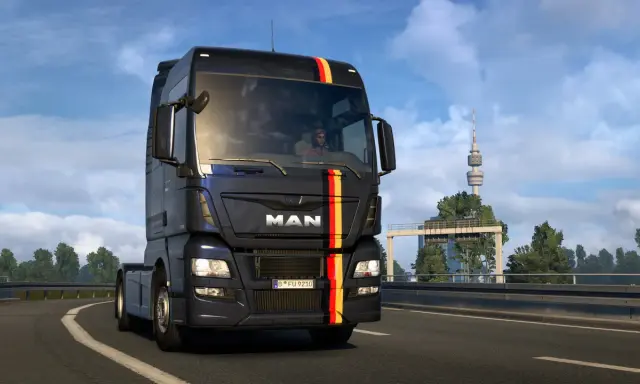 Ciemny MAN z niemieckimi barwami na masce jedzie autostradą. W tle wieża telewizyjna, typowa dla krajobrazu w grze german truck simulator.