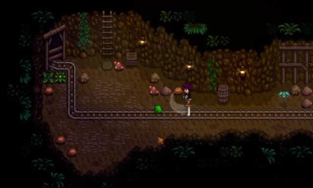Postać w kopalni Stardew Valley walczy z zielonym potworem. To świetny moment na poradnik!