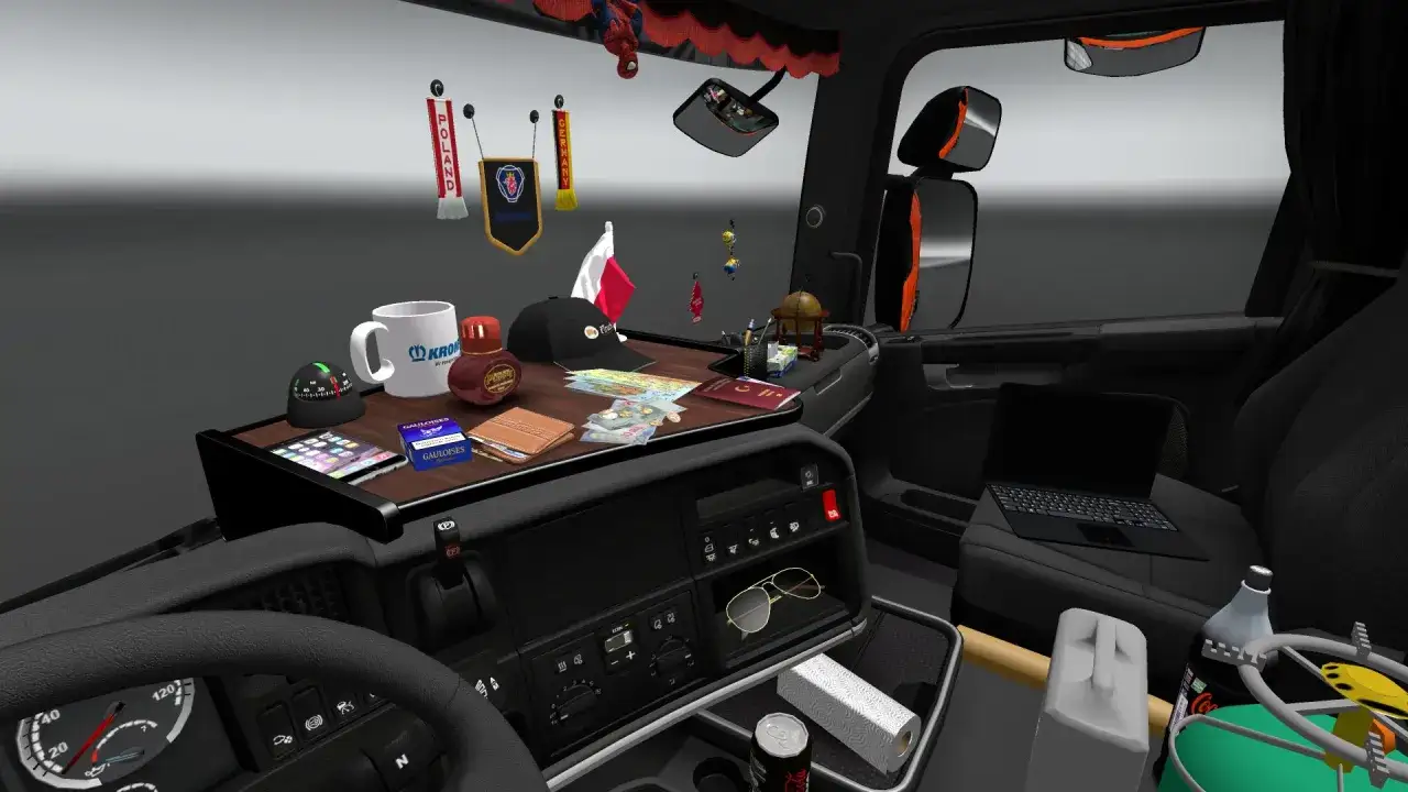 Kabina ciężarówki pełna drobnych przedmiotów: kubek, pieniądze, paszport, telefon, okulary, laptop i flagi. To typowe cabin accessories ets2.